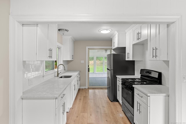 kitchen with gas range, sink, tasteful backsplash, light hardwood / wood-style floors, and white cabinets