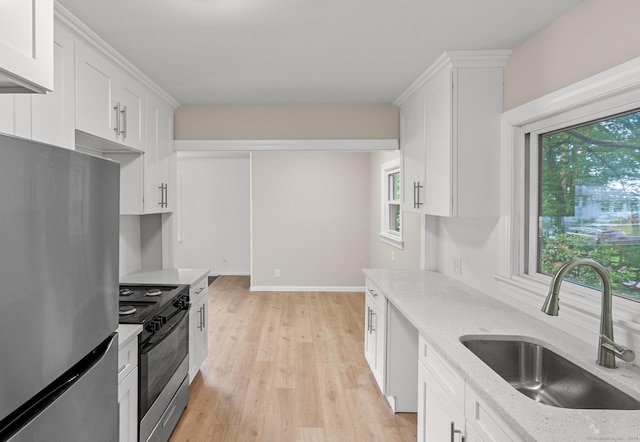 kitchen with stainless steel appliances, white cabinetry, plenty of natural light, and sink