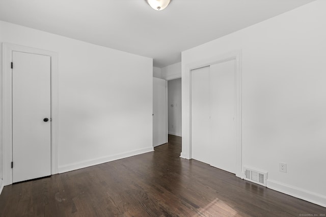 unfurnished bedroom featuring dark hardwood / wood-style flooring and a closet