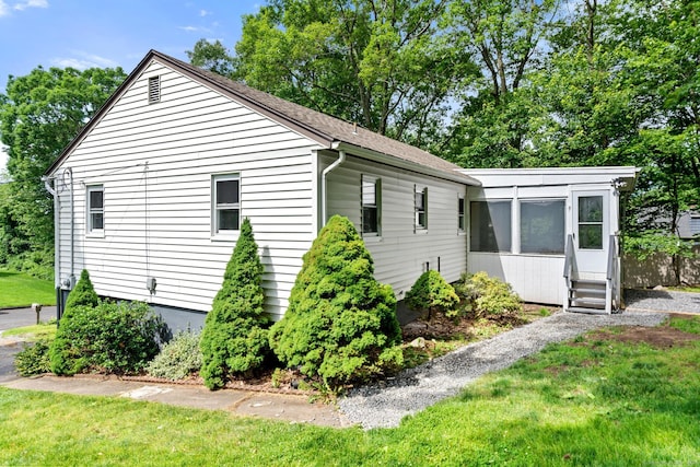 view of property exterior with a lawn and a sunroom