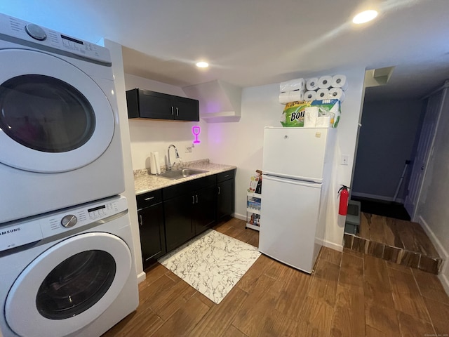 laundry area featuring dark wood-type flooring, stacked washer and clothes dryer, and sink