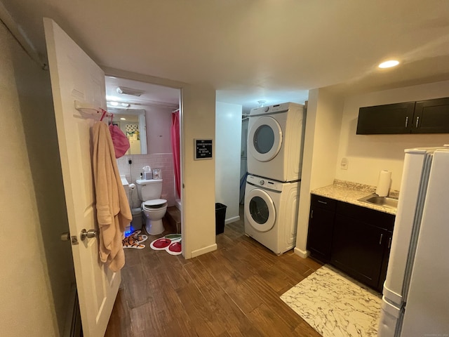 laundry room featuring dark hardwood / wood-style flooring and stacked washer / dryer