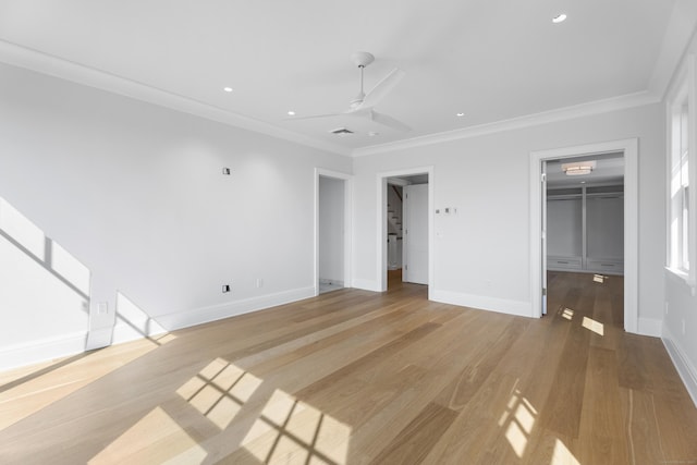 unfurnished bedroom with ceiling fan, light hardwood / wood-style flooring, a walk in closet, a closet, and ornamental molding