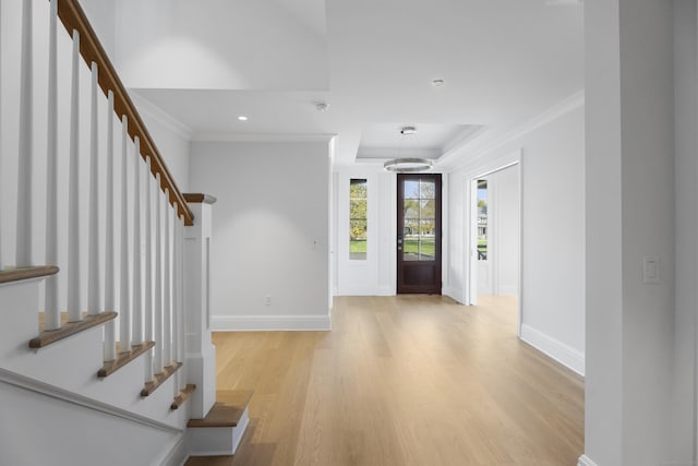 foyer entrance with light hardwood / wood-style floors, ornamental molding, and a chandelier