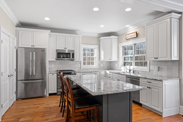 kitchen featuring white cabinets, appliances with stainless steel finishes, light hardwood / wood-style floors, and a kitchen island