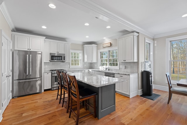 kitchen featuring a center island, light wood-type flooring, stainless steel appliances, and white cabinetry