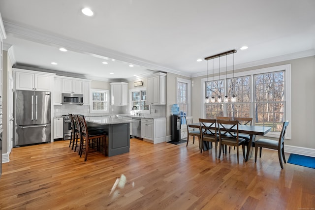 kitchen featuring a center island, hanging light fixtures, light hardwood / wood-style floors, a breakfast bar, and appliances with stainless steel finishes