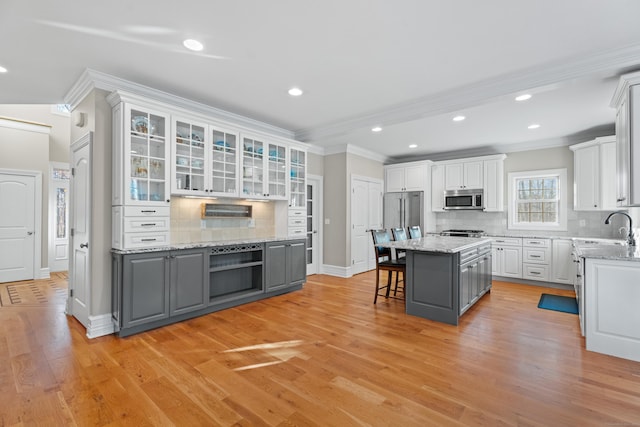 kitchen featuring white cabinetry, light hardwood / wood-style flooring, a kitchen bar, decorative backsplash, and a kitchen island