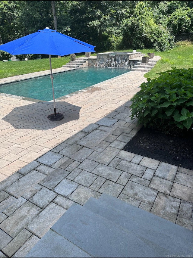 view of swimming pool featuring pool water feature and a patio