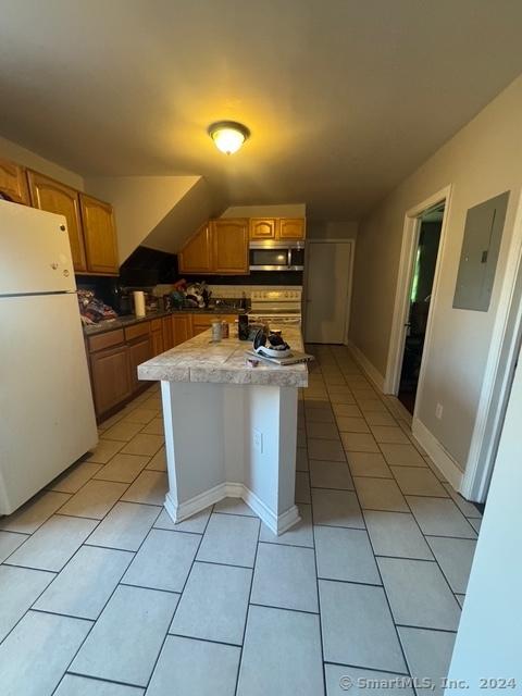 kitchen with decorative backsplash, white refrigerator, light tile patterned floors, and electric panel