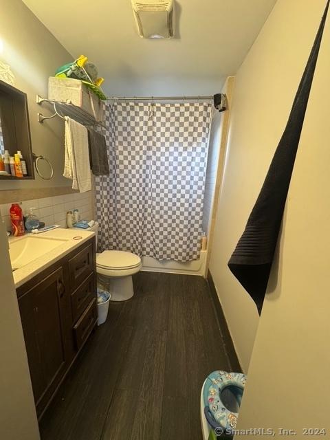 full bathroom featuring decorative backsplash, shower / tub combo, vanity, wood-type flooring, and toilet