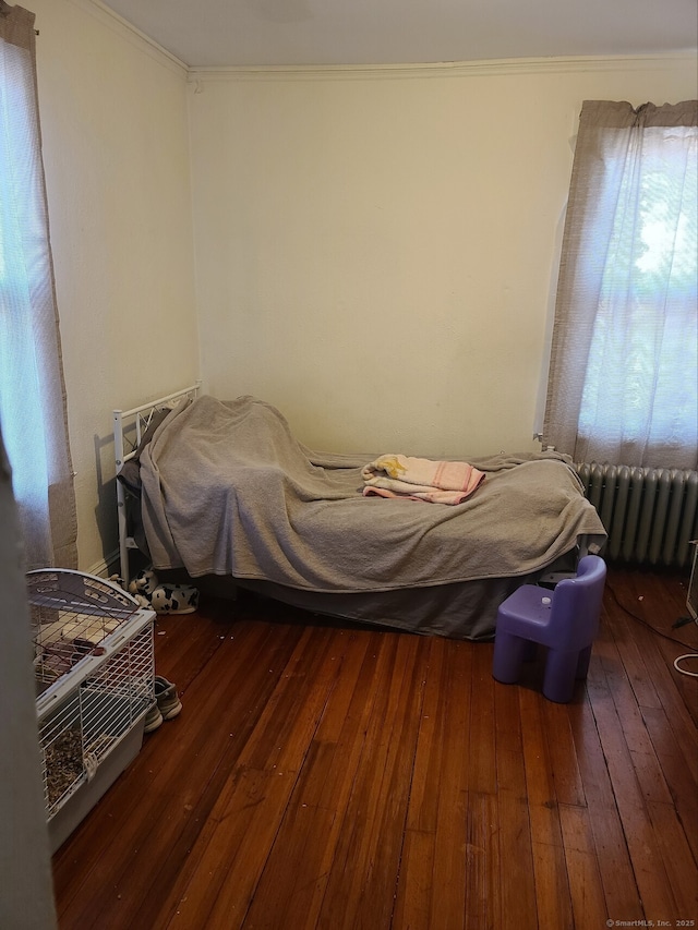 bedroom featuring dark hardwood / wood-style flooring, radiator heating unit, and crown molding