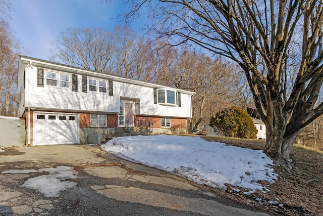 bi-level home featuring brick siding, aphalt driveway, and an attached garage