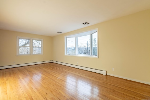 spare room with baseboards, light wood-style flooring, and a healthy amount of sunlight