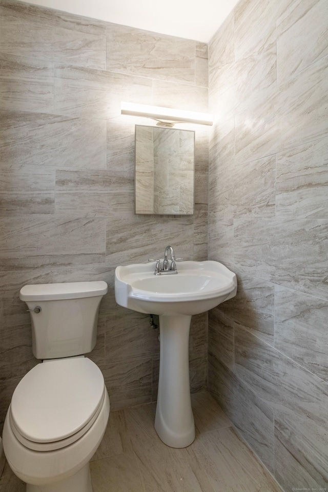 half bathroom with toilet and tile walls