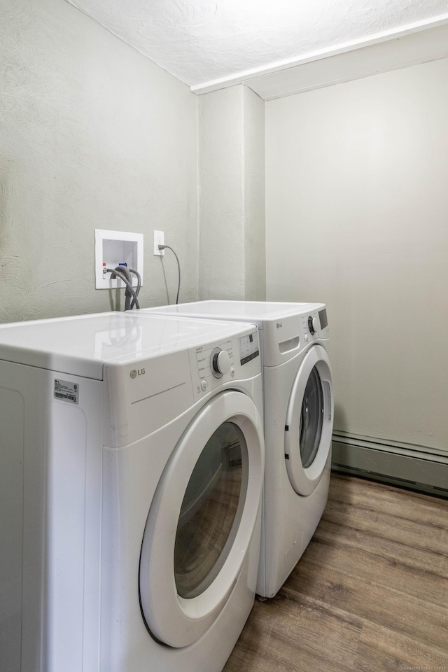 clothes washing area featuring laundry area, independent washer and dryer, baseboard heating, and wood finished floors