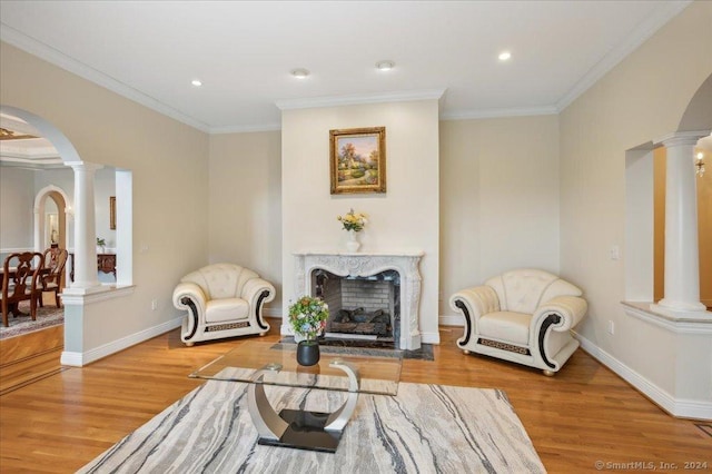 sitting room with crown molding, a fireplace, hardwood / wood-style floors, and ornate columns