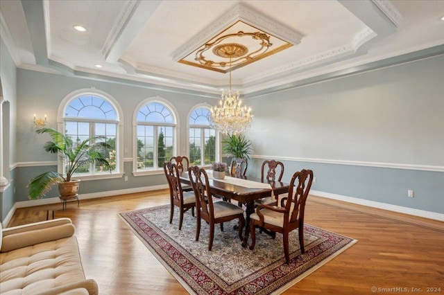 dining room with crown molding, hardwood / wood-style flooring, a raised ceiling, and a chandelier