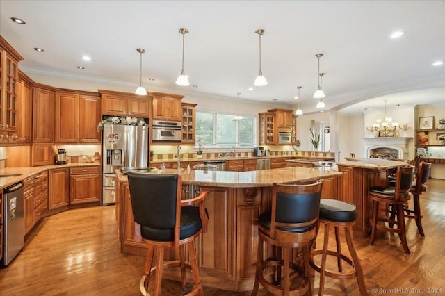 kitchen with pendant lighting, a kitchen bar, stainless steel appliances, and a large island with sink