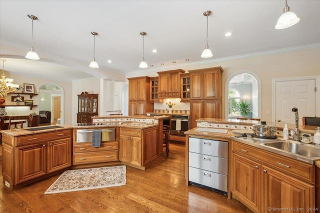 kitchen featuring sink, hardwood / wood-style flooring, hanging light fixtures, a kitchen island, and oven