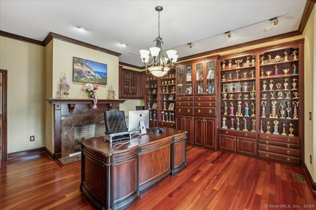 office space featuring crown molding, rail lighting, a premium fireplace, dark hardwood / wood-style floors, and a notable chandelier