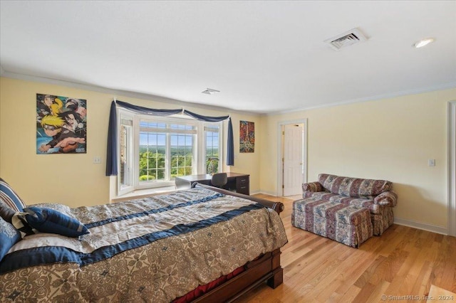 bedroom with ornamental molding and light hardwood / wood-style floors