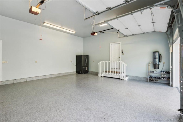 garage with a garage door opener and stainless steel fridge