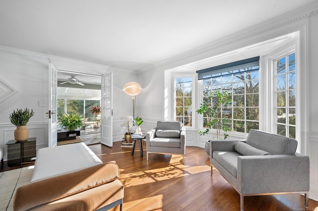 interior space with crown molding, a wainscoted wall, hardwood / wood-style flooring, and a decorative wall