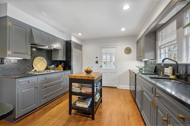 kitchen featuring light wood-style flooring, a sink, appliances with stainless steel finishes, gray cabinets, and dark countertops