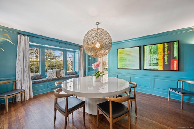 dining area with a decorative wall and dark wood-type flooring