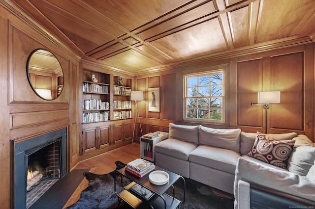 living room with built in shelves, wooden walls, wood finished floors, wooden ceiling, and a lit fireplace