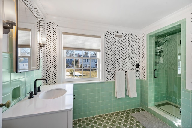 bathroom with tile patterned flooring, crown molding, vanity, a shower stall, and tile walls