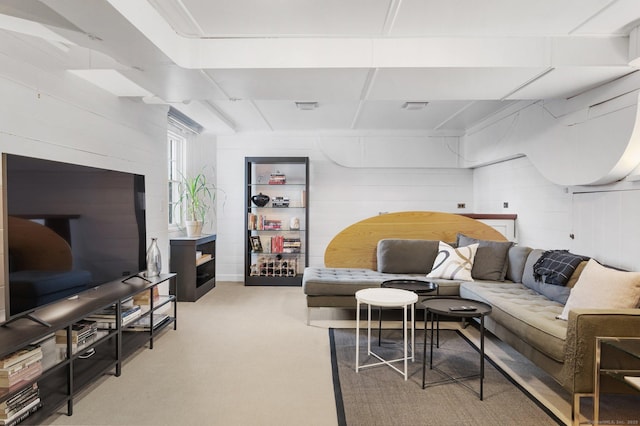 living area with light carpet, visible vents, and concrete block wall