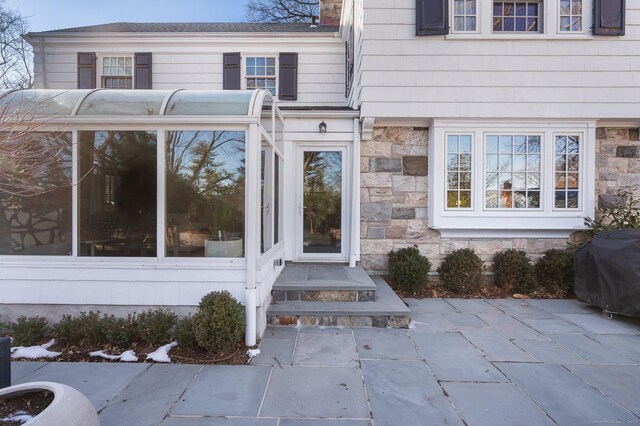 doorway to property featuring stone siding and a patio area