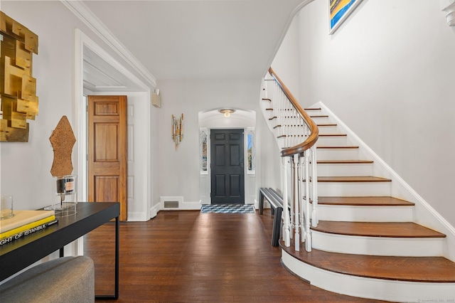 entryway featuring baseboards, visible vents, arched walkways, dark wood-style flooring, and stairs