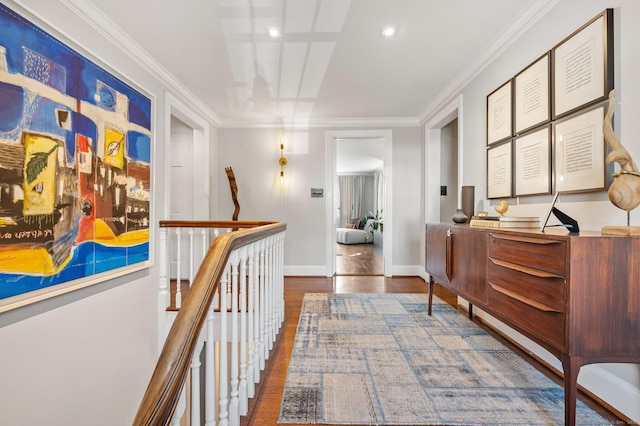 hall with dark wood-style floors, baseboards, crown molding, and an upstairs landing