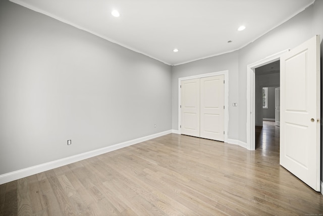 unfurnished bedroom featuring crown molding, a closet, and light hardwood / wood-style floors