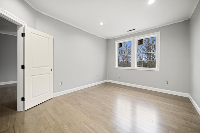 empty room with crown molding and light hardwood / wood-style flooring