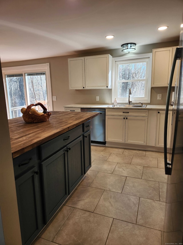 kitchen with white cabinetry, stainless steel dishwasher, butcher block counters, and sink