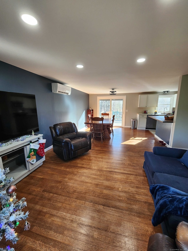 living room with a wall mounted AC, dark wood-type flooring, and sink