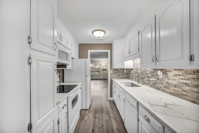 kitchen featuring white cabinetry, sink, light stone countertops, light hardwood / wood-style flooring, and white appliances