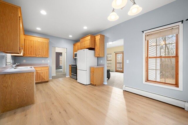 kitchen with white refrigerator, light wood-type flooring, baseboard heating, stainless steel range, and decorative light fixtures