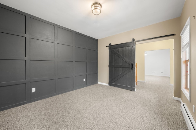 carpeted spare room with a barn door and a baseboard radiator