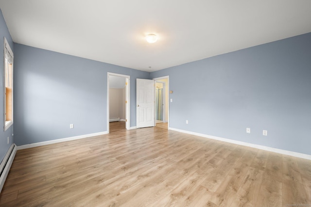 unfurnished room with baseboard heating and light hardwood / wood-style flooring