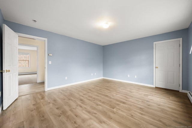 spare room with a baseboard heating unit and light wood-type flooring