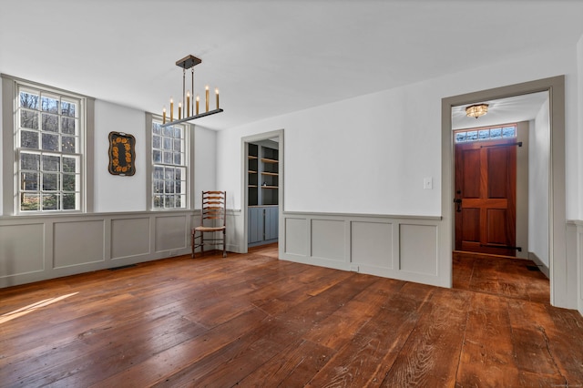 unfurnished dining area featuring a chandelier and dark hardwood / wood-style floors