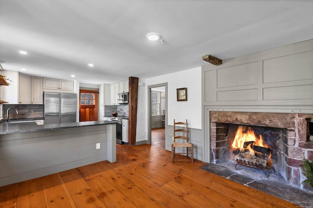 kitchen featuring sink, stainless steel appliances, kitchen peninsula, hardwood / wood-style floors, and decorative backsplash