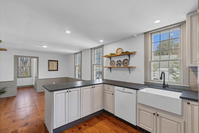 kitchen featuring kitchen peninsula, white dishwasher, white cabinetry, and dark wood-type flooring