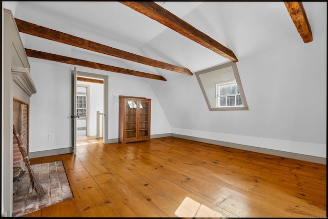 unfurnished living room featuring a fireplace, lofted ceiling with beams, and light wood-type flooring