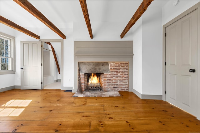 unfurnished living room featuring hardwood / wood-style floors, beam ceiling, and a fireplace